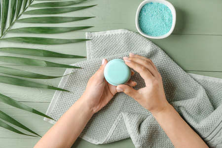 Woman with cosmetics for spa procedures at wooden tableの写真素材