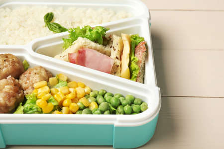 School lunch box with tasty food on white wooden background