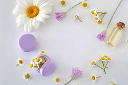 Frame made of cosmetic products with chamomile flowers on white backgroundの写真素材