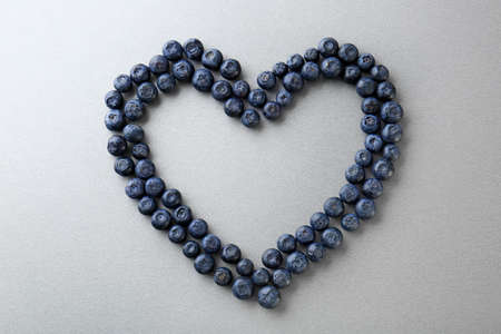Heart made of ripe blueberry on gray background