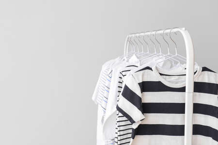 Stylish kid clothes hanging on rack against light backgroundの写真素材