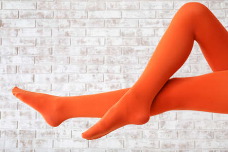 Stylish young woman in tights on brick backgroundの写真素材
