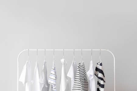 Stylish kid clothes hanging on rack against light backgroundの写真素材