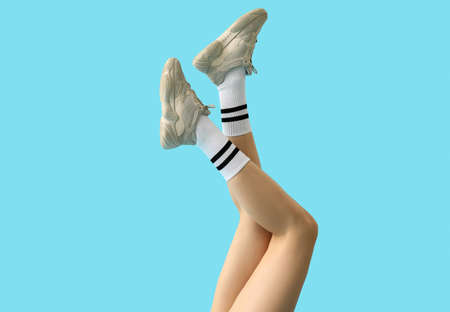 Stylish young woman in shoes and socks on color backgroundの写真素材