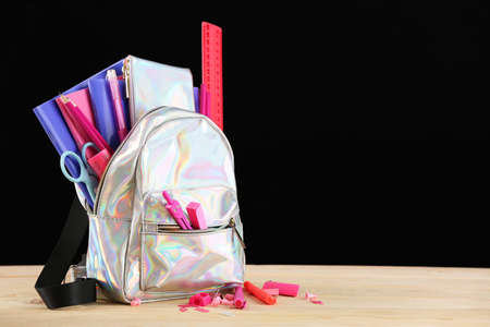 School backpack with stationery on table in classroom