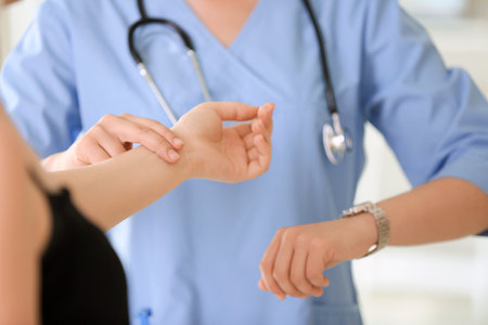 Doctor measuring pulse of young woman in clinicの写真素材