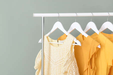 Rack with hanging clothes on color backgroundの写真素材