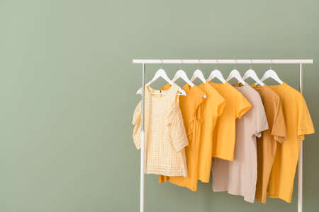 Rack with hanging clothes on color backgroundの写真素材