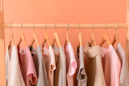 Rack with hanging clothes on color backgroundの写真素材