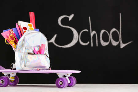 School backpack with stationery on table in classroom