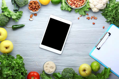 Modern tablet computer with fresh products on wooden backgroundの写真素材