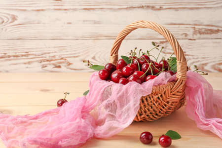 Wicker basket with ripe cherry on wooden backgroundの写真素材