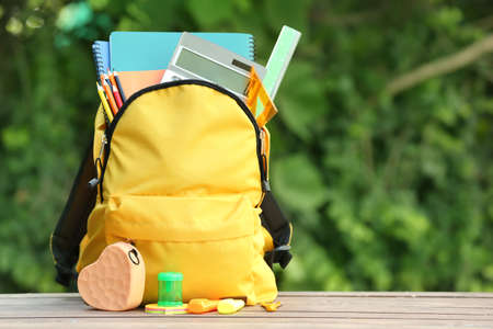 School backpack with stationery on table outdoorsの写真素材