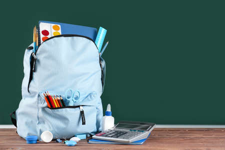 School backpack with stationery on table in classroom