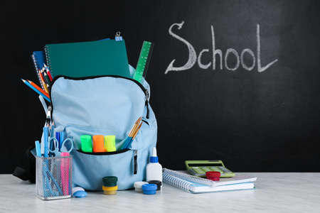 School backpack with stationery on table in classroom
