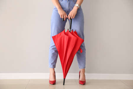 Young woman with stylish umbrella near light wallの写真素材