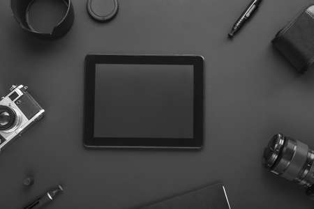 Tablet computer and set of photographer's equipment on dark backgroundの写真素材
