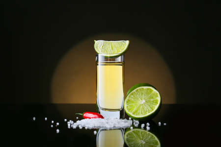 Shot of tasty tequila with lime, salt and chili pepper on dark backgroundの写真素材