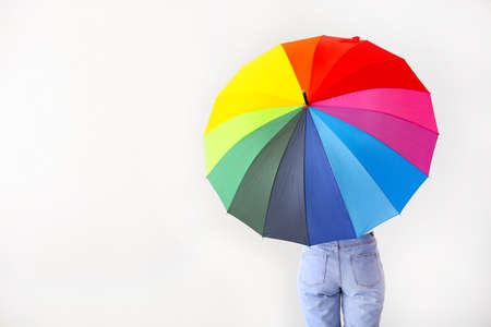 Young woman with stylish umbrella on light backgroundの写真素材