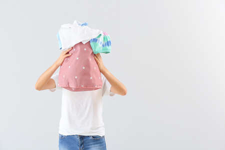 Beautiful young woman with laundry on light backgroundの写真素材