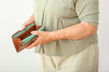 Elderly woman with empty wallet on white background, closeup. Concept of poverty in retirementの写真素材