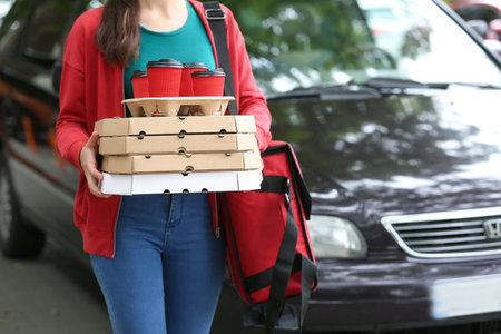 Female worker of food delivery service near car outdoorsの写真素材