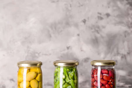 Jars with different canned olives and beans on grunge backgroundの写真素材