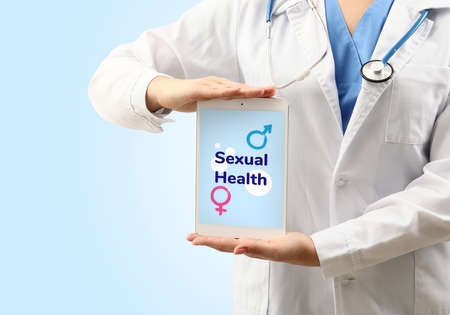 Female gynecologist with tablet computer on color background. Concept of sexual healthの写真素材