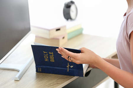 Religious young woman reading Bible at homeの写真素材
