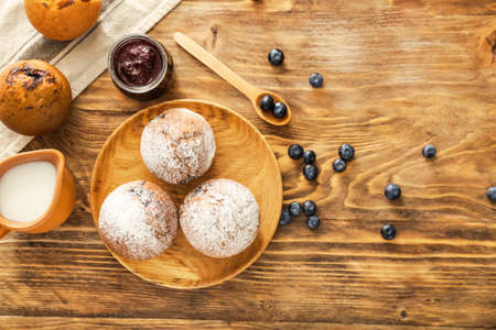 Tasty blueberry muffins with jam and milk on wooden tableの写真素材