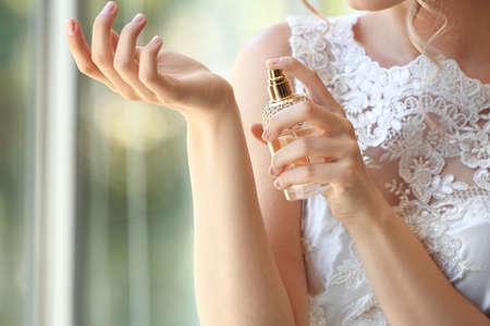 Beautiful young bride with bottle of perfume indoors, closeupの写真素材