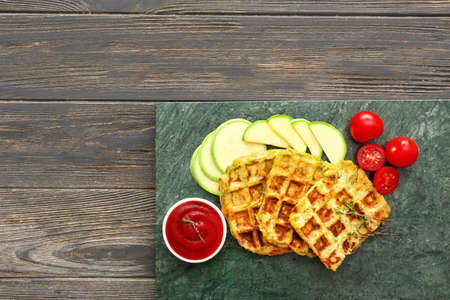 Board with tasty squash waffles and sauce on wooden tableの写真素材