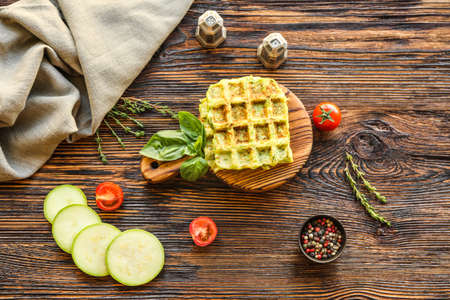 Tasty squash waffles with tomatoes and spices on wooden tableの写真素材