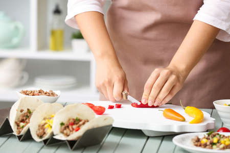 Woman preparing tasty fresh tacos in kitchen