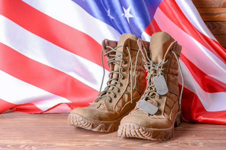 Military boots and USA flag on wooden table