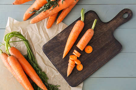 Cutting board with fresh carrots on tableの写真素材