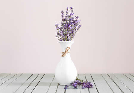 Beautiful lavender flowers in vase on table against light backgroundの写真素材