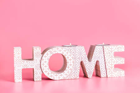 Candle holder in shape of word HOME on color backgroundの写真素材