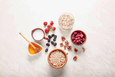 Oat flakes with milk, honey, nut and berries on light tableの写真素材