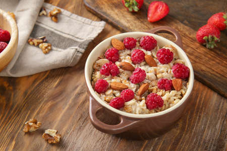 Pot with tasty sweet oatmeal, raspberry and almond on wooden tableの写真素材