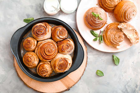Baking tray with tasty cinnamon buns on table
