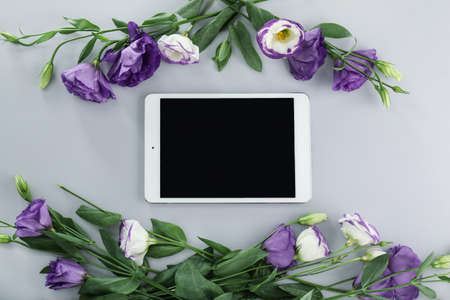 Modern tablet computer with flowers on gray background