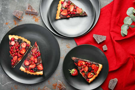 Plates with pieces of tasty chocolate strawberry cake on gray backgroundの写真素材