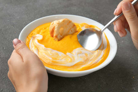 Woman eating tasty cream soup at table, closeupの写真素材