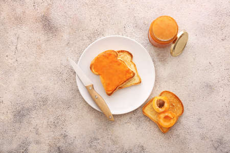 Tasty apricot jam with bread slices on gray backgroundの写真素材