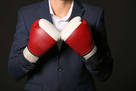 Businessman in boxing gloves against dark backgroundの写真素材