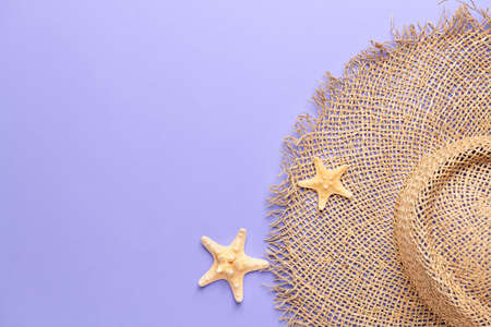 Beach hat and starfish on color background