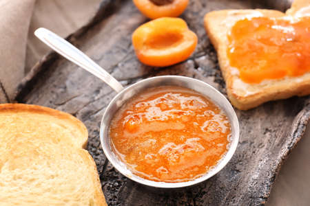 Tasty apricot jam and bread slices on plate, closeup