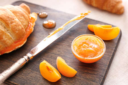Tasty apricot jam with croissant on wooden board, closeupの写真素材