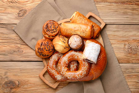 Board with tasty pastries on wooden background